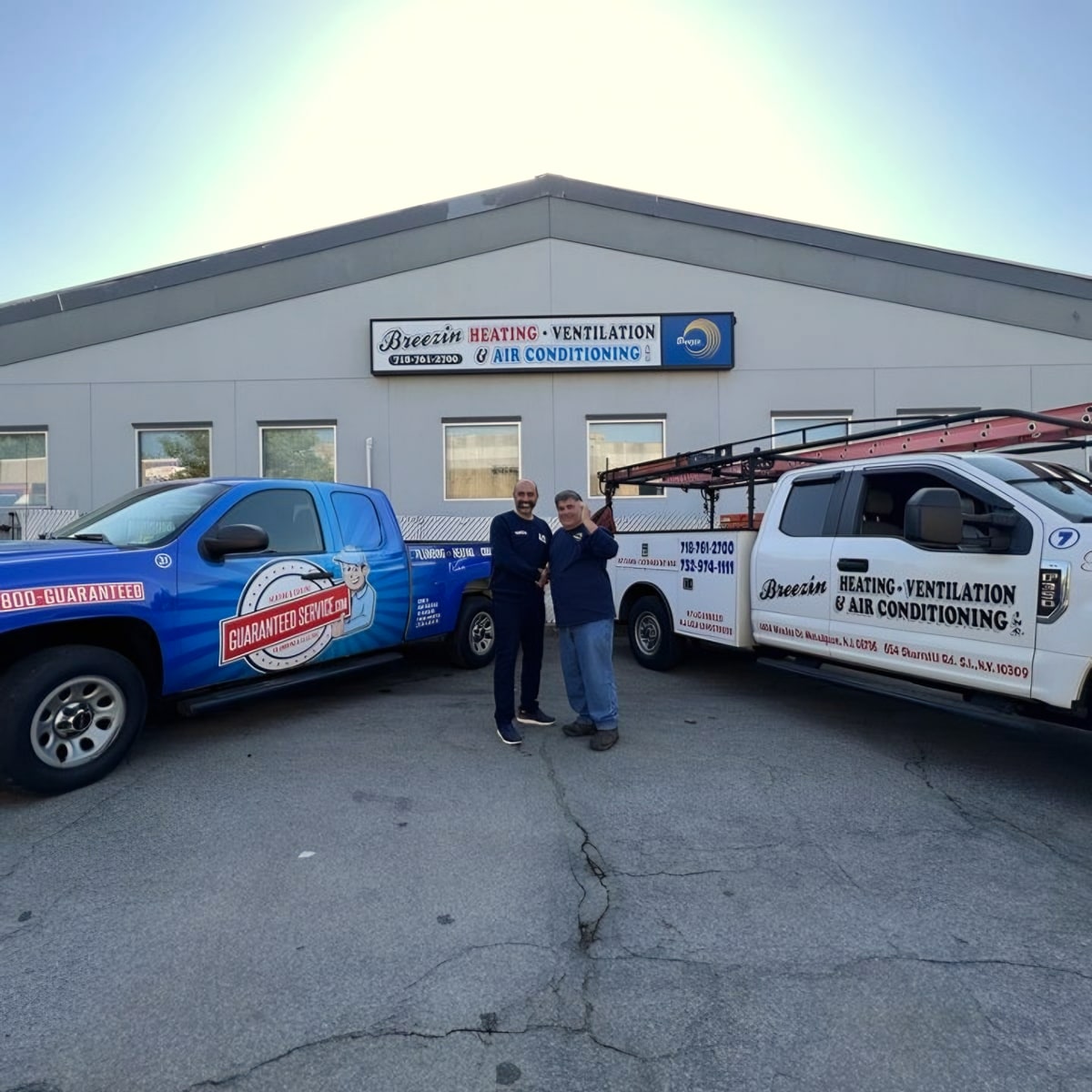 Two men shaking hands between two Breezin service trucks in front of building