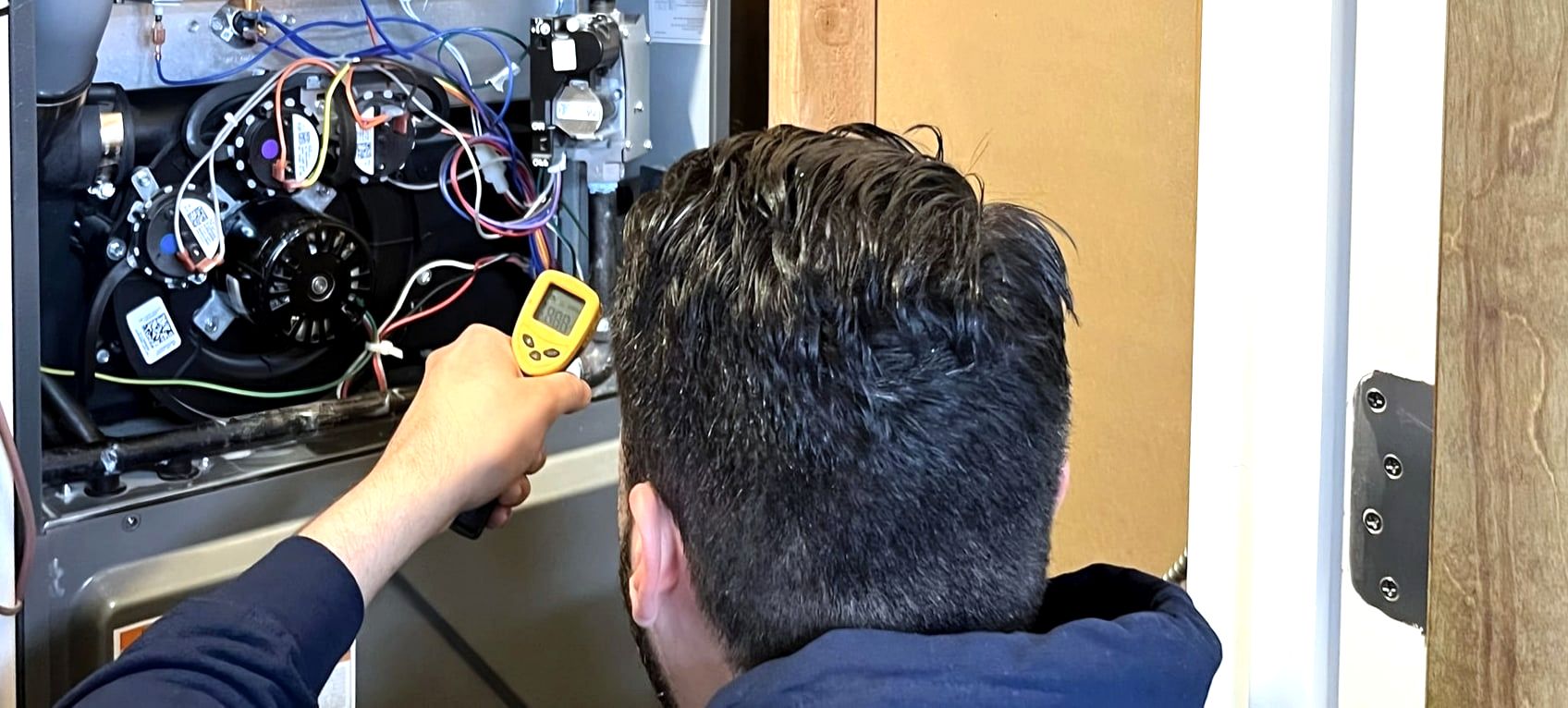 Technician using infrared thermometer on open furnace, wide crop